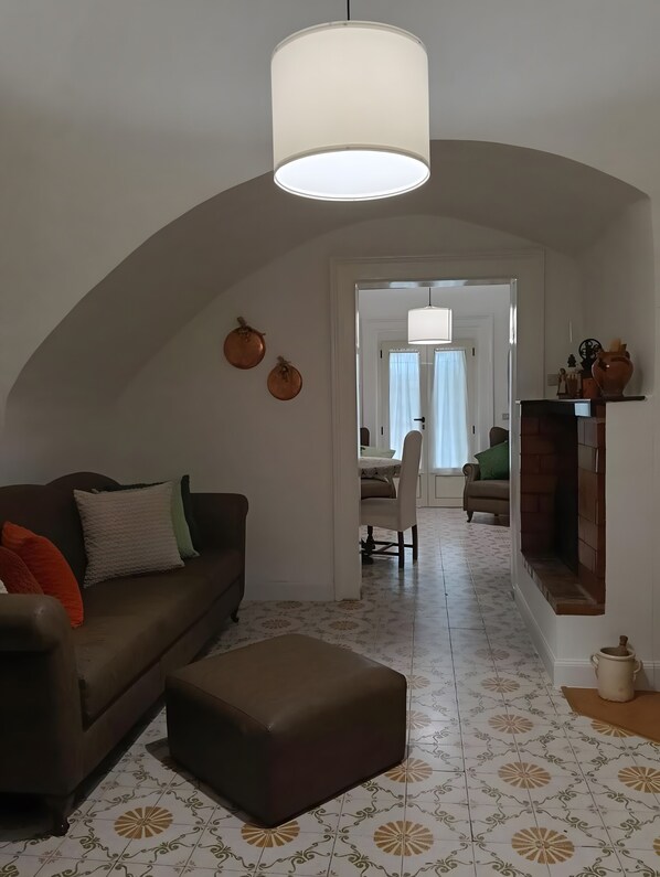 A living room with a sofa, ottoman, and a hanging light fixture.