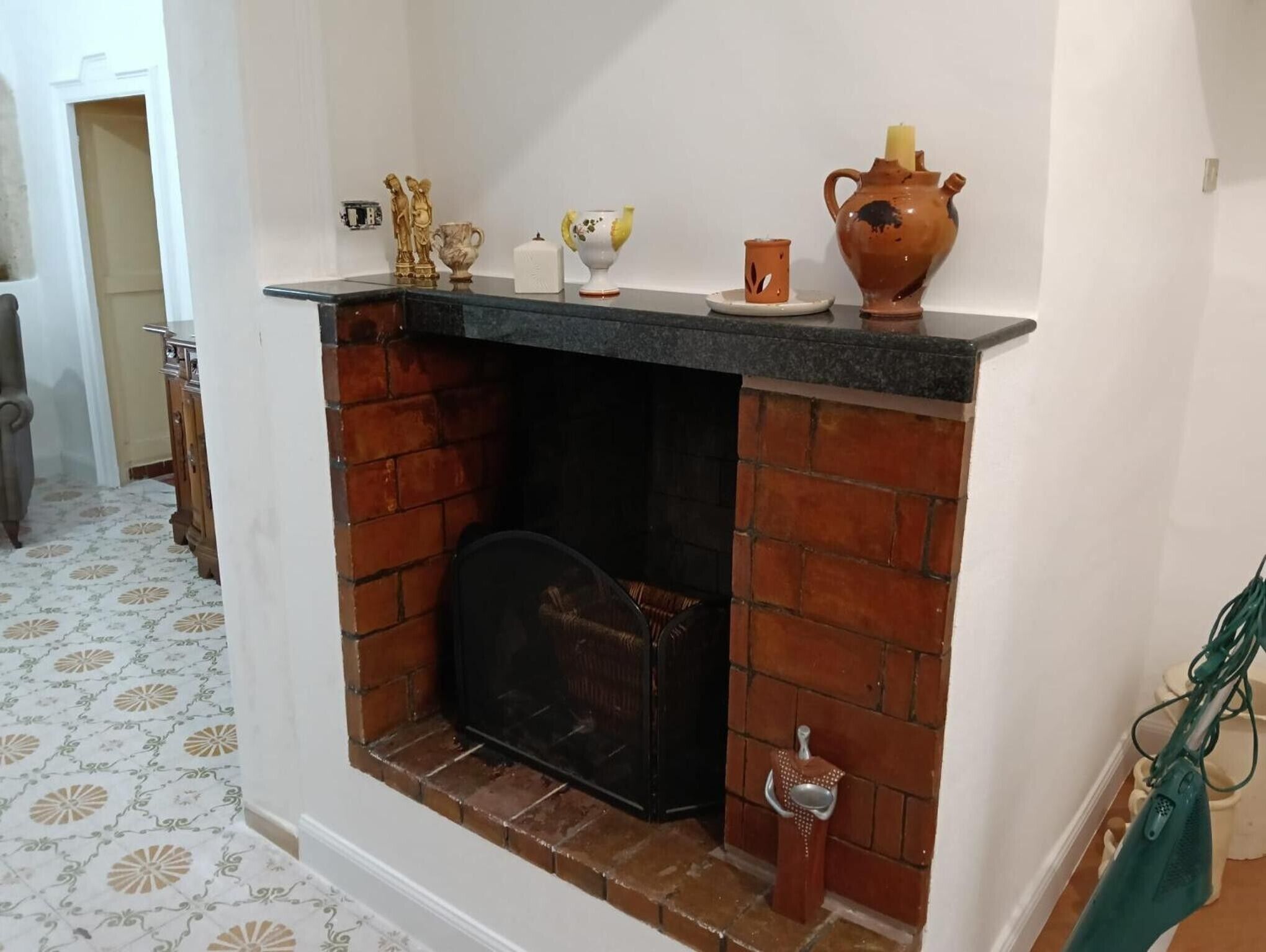 A fireplace with a brick surround, a mantel with decorative items, and a patterned floor.