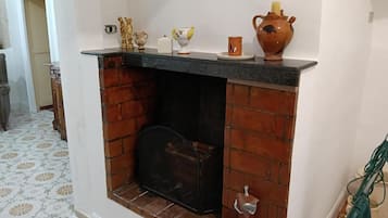 A fireplace with a brick surround, a mantel with decorative items, and a patterned floor.
