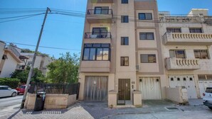A multi-story residential building with balconies, a gated entrance, and a clear sky. - Beautiful 2BR Apartment in Swieqi with Balcony (Swieqi)