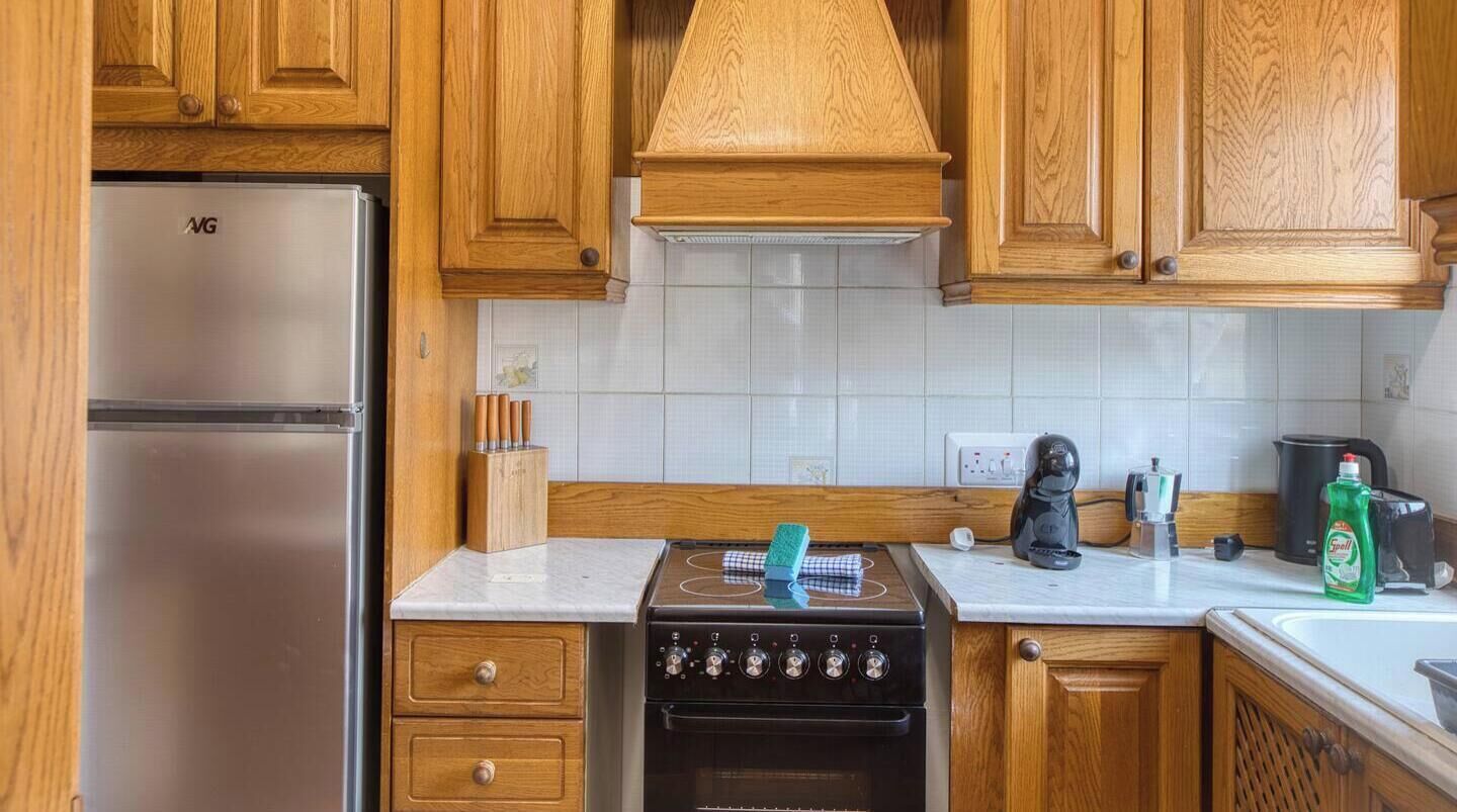 Une cuisine avec des meubles en bois, un réfrigérateur en acier inoxydable, une cuisinière et une machine à café.