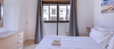 Habitación de hotel con cama, cómoda, ventana con cortinas y un cuadro en la pared.