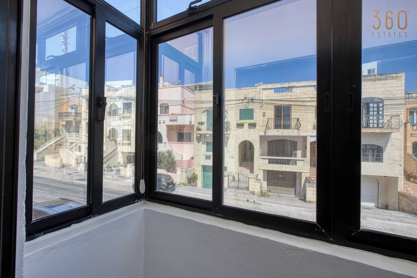 A room with large windows offering views of neighboring buildings.