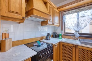 Eine Küche mit Holzausstattung, einem Herd, einem Spülbecken und einem Fenster mit Vorhang.