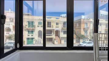 A window with a view of a residential area, including buildings and a street.