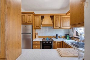 Una cucina compatta con mobili in legno, un frigorifero in acciaio inossidabile, un fornello e un lavello.