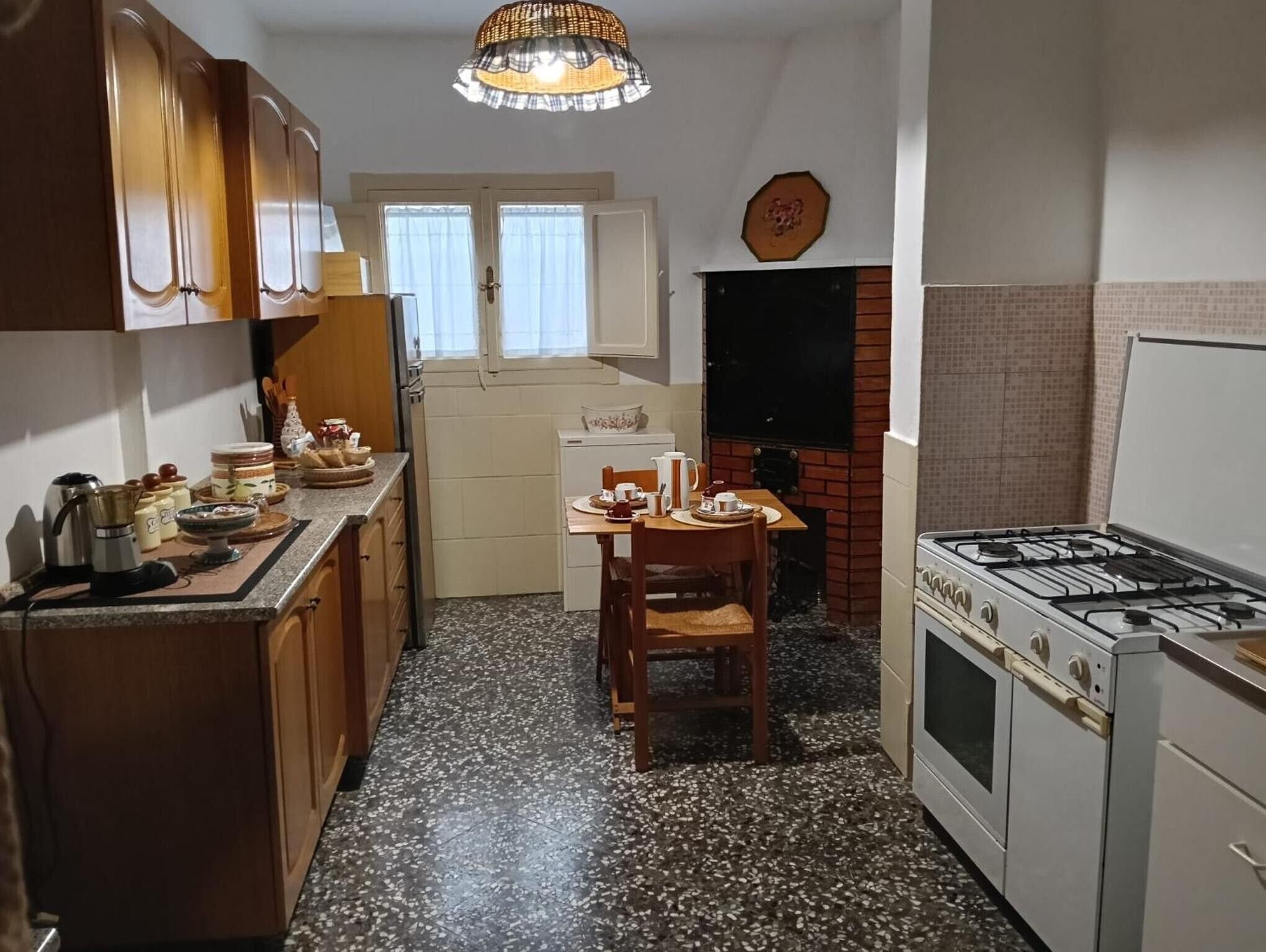 A compact kitchen with a gas stove, wooden cabinets, a dining table, and a window.
