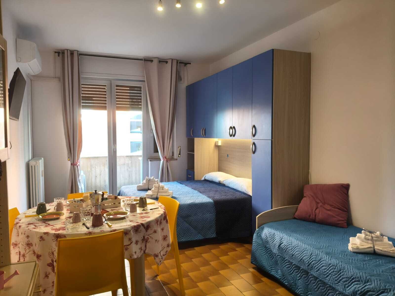 A compact bedroom with a bed, a small table with breakfast items, and a chair.