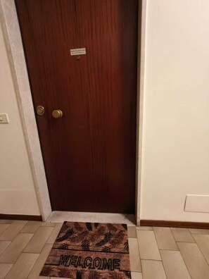 Eine Holztür mit einer Fußmatte, auf der 'WELCOME' steht.