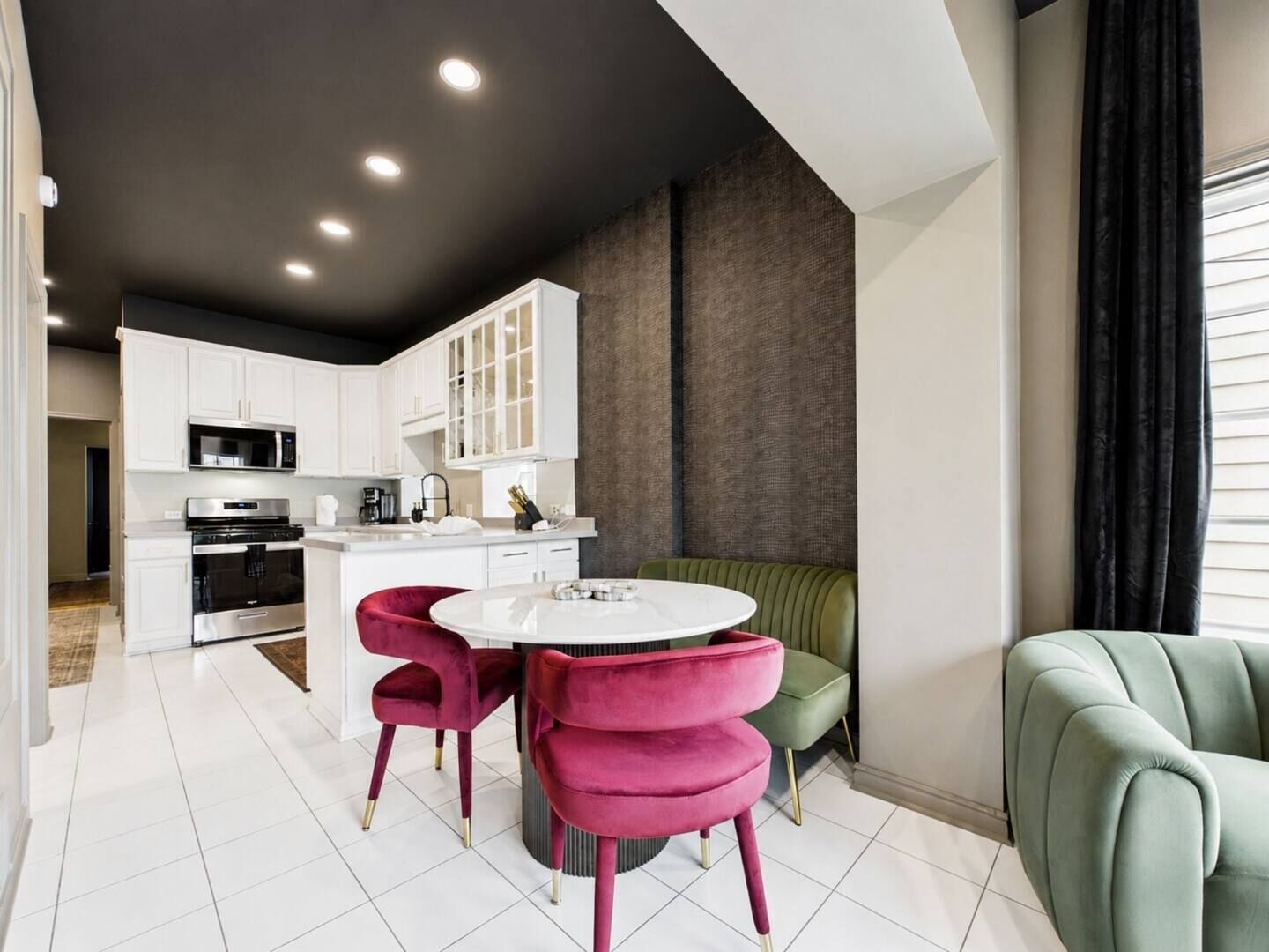 A modern kitchen with white cabinetry, a central island, and a dining area with two chairs.