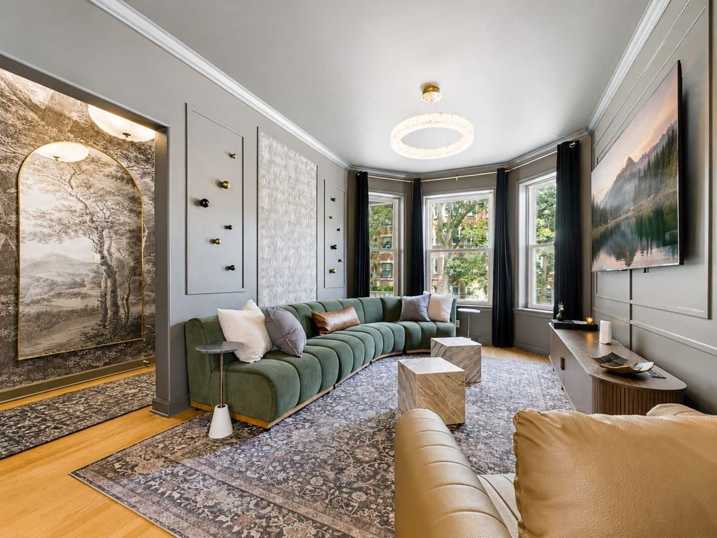 Ein modernes Wohnzimmer mit einem grünen Ecksofa, einem gemusterten Teppich und Bildern an den Wänden.