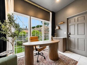 A modern office space with a large window, a desk, a chair, and a potted plant.