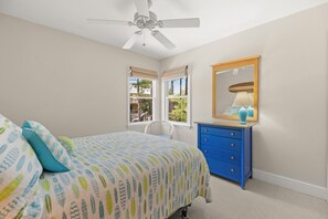Ein Schlafzimmer mit einem Bett, einem Schminktisch, einem Spiegel und einem Deckenventilator.