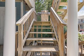 A wooden staircase leading to a covered outdoor area with a grill. - Village at Ocean Hill 26: Pool | Nearby Beach (Corolla)