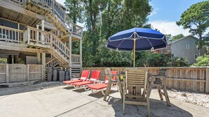 Eine Terrasse mit Holzdeck, roten Lounge-Sesseln, einem Tisch und einem blauen Sonnenschirm.