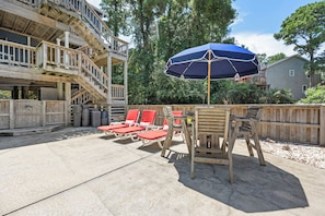 Eine Terrasse mit Holzdeck, roten Lounge-Sesseln, einem Tisch und einem blauen Sonnenschirm.