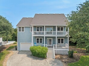 Ein zweistöckiges Wohnhaus mit Veranda, Garage und kleinem Vorgarten.