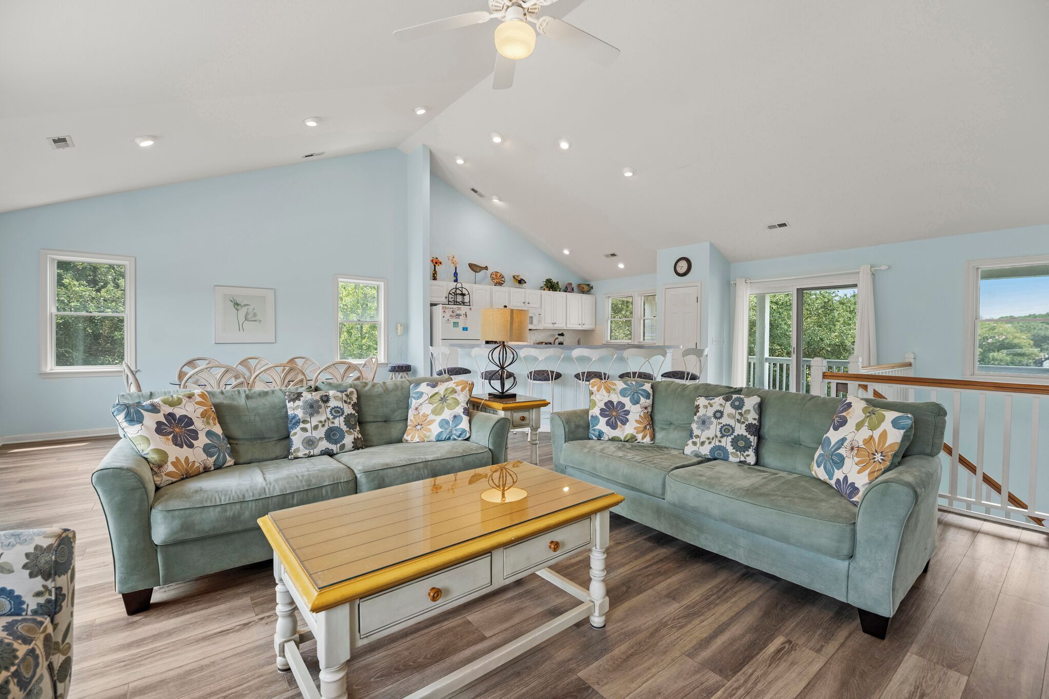 A spacious living room with a large sectional sofa, a wooden coffee table, and a dining area with a kitchen in the background.