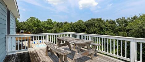 A wooden deck with a picnic table and chairs, surrounded by a white railing.
