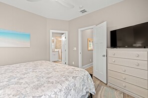 Une chambre à coucher avec un lit, une commode, un téléviseur et un tableau accroché au mur.