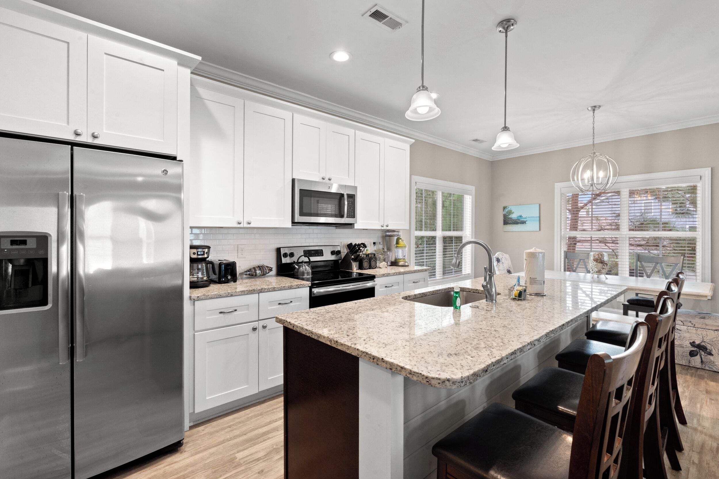 A modern kitchen with stainless steel appliances, white cabinetry, and a granite countertop.