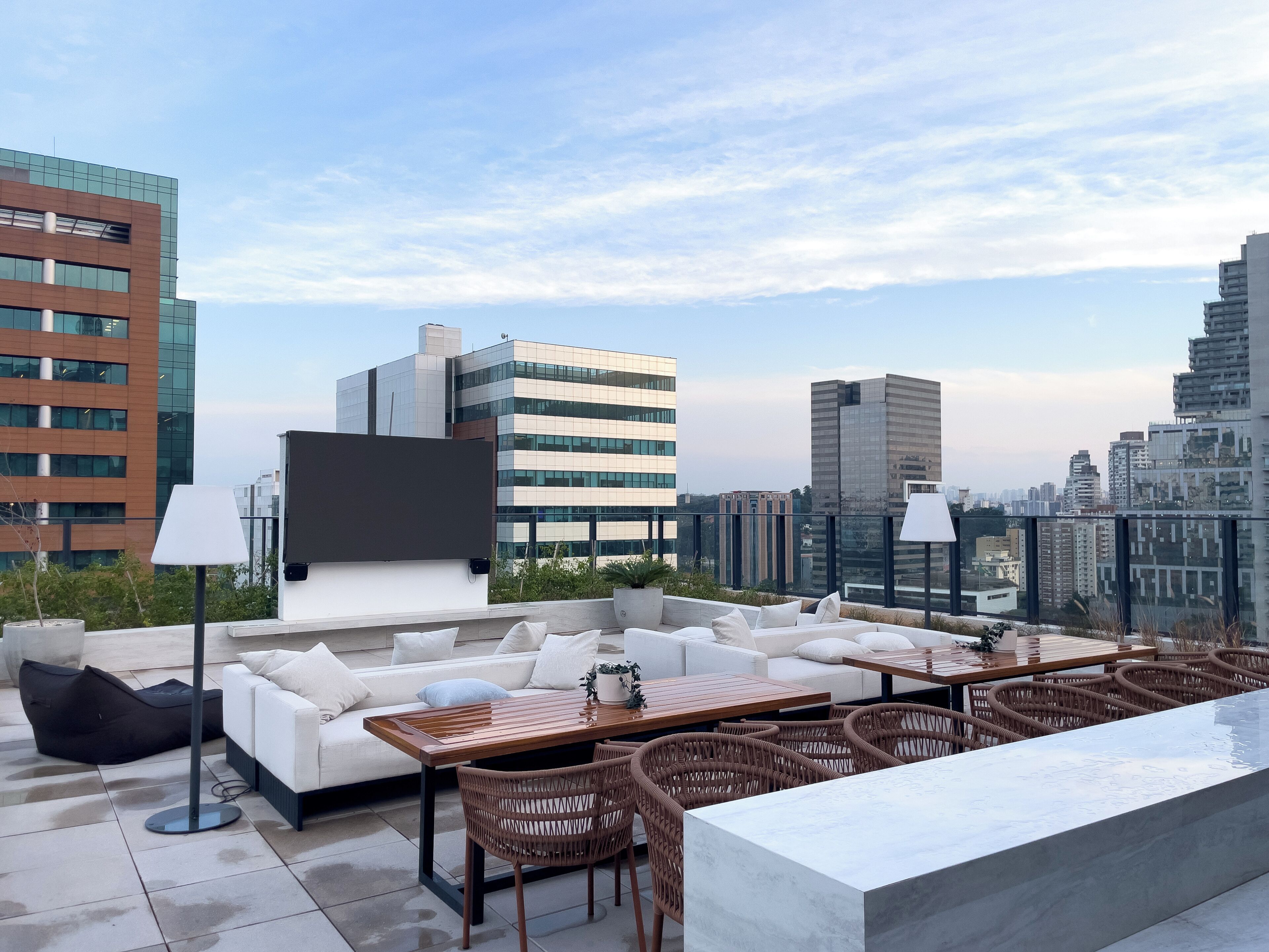 Une terrasse sur le toit, aménagée avec un canapé, une table à manger, des chaises et offrant une vue panoramique sur la ville.