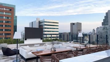 Une terrasse sur le toit, aménagée avec un canapé, une table à manger, des chaises et offrant une vue panoramique sur la ville.