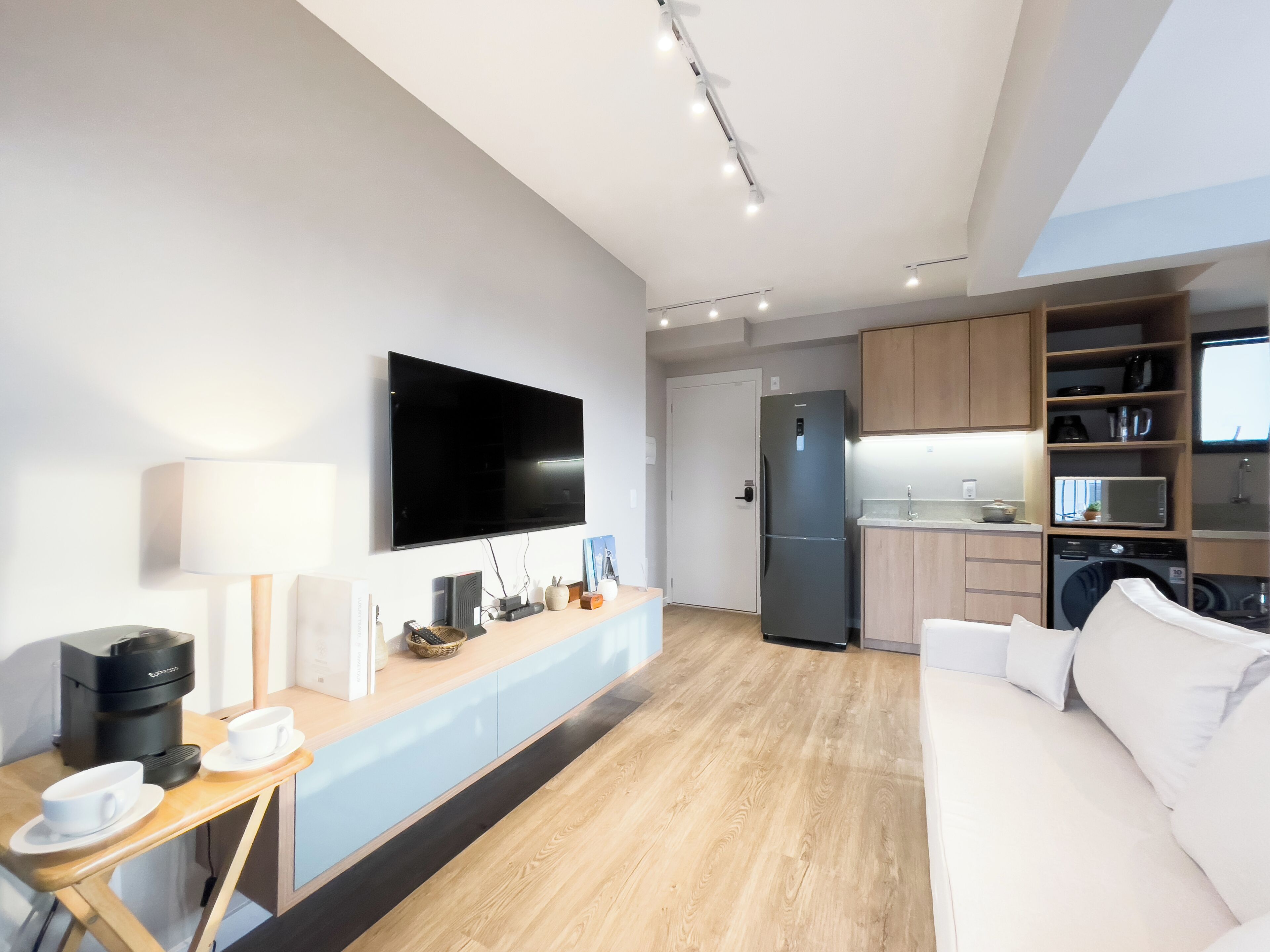 Un espace de vie moderne comprenant un téléviseur à écran plat, un coin cuisine et un espace détente avec un canapé.