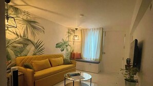 A living room with a sofa, a coffee table, a TV, and a window with curtains. - Entire rental unit in Bengaluru, India (Bengaluru)