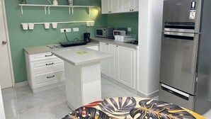 A compact kitchen with white cabinets, a stainless steel refrigerator, and a microwave. - Entire rental unit in Bengaluru, India (Bengaluru)