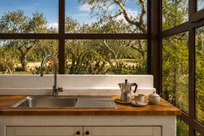 A kitchen with a stainless steel sink, a coffee maker, and a cup on the counter. - Nina Homes: Trulli Dodò (Monopoli)