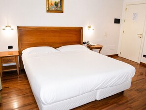 Une chambre d’hôtel avec un grand lit, une tête de lit en bois, des tables de chevet et un tableau au mur.