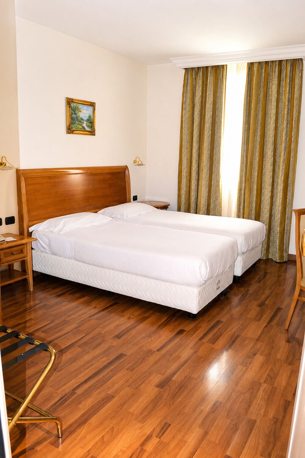 Una habitación de hotel con una cama doble, una mesita de noche, una lámpara y un cuadro en la pared.