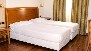 Una habitación de hotel con una cama doble, una mesita de noche, una lámpara y un cuadro en la pared.