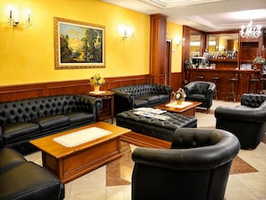 A hotel lobby with leather sofas, a bar area, and a painting on the wall. - Hotiday Reggio Emilia Gaida (Reggio nell'Emilia)