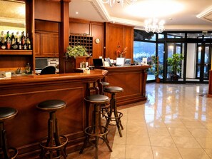 Zona de bar con mobiliario de madera, una barra y taburetes.