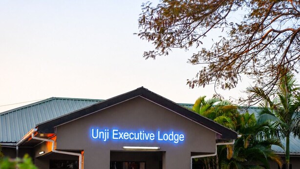 The Unji Executive Lodge with a clear entrance, a signboard, and a paved area in front.