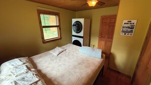 A bedroom with a bed, a ceiling fan, a washing machine, and a door. - Convenient Lakeside House (Rangeley)