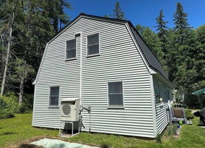 Ein zweistöckiges Haus mit einem zentralen Schornstein, einer kleinen Veranda und einer Klimaanlage.