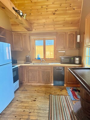 Eine Küche mit Holzausstattung, einem blauen Kühlschrank, einer Mikrowelle und einem Geschirrspüler.
