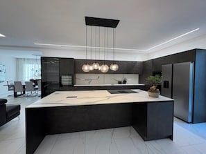 A modern kitchen with a central island, pendant lighting, and a built-in refrigerator. - Villa Alba, in the heart of Franciacorta (Villa Pedergnano)