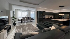 Un salon moderne comprenant un canapé, un téléviseur et un coin repas avec une table et des chaises.