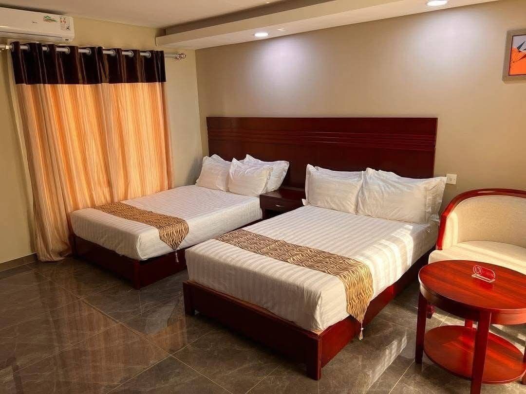 A hotel room with two beds, a chair, and a small table.