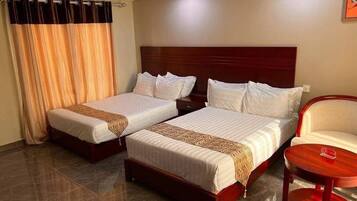 A hotel room with two beds, a chair, and a small table.