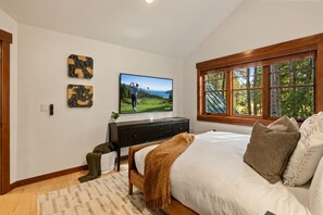 Un dormitorio con cama, televisor, ventana con vistas y una obra de arte colgada en la pared.