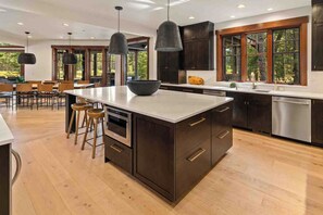 A modern kitchen with a large island, dark cabinetry, stainless steel appliances, and pendant lighting. - 1PM In/Out | Play All Day / Soak All Night | GameRoom + Swim Spa (Cle Elum)