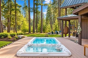 A hot tub in a forested area with a deck and outdoor furniture. - 1PM In/Out | Play All Day / Soak All Night | GameRoom + Swim Spa (Cle Elum)