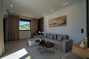 Ein modernes Wohnzimmer mit einer Couch, zwei Couchtischen und einem Gemälde an der Wand.