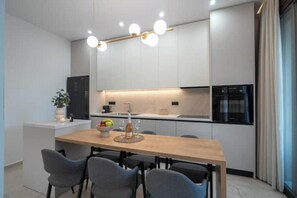 Eine moderne Küche mit einem Holztisch, grauen Stühlen und einem eingebauten Backofen.