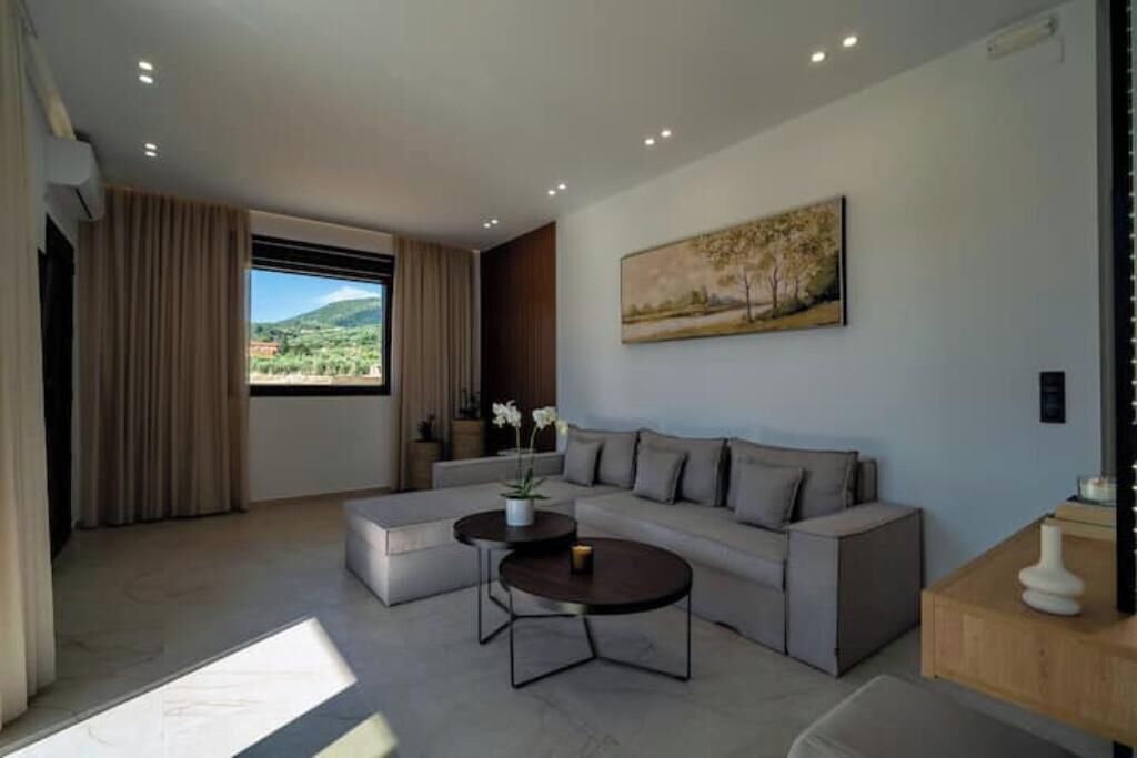 A modern living room with a sofa, two coffee tables, and a painting on the wall.